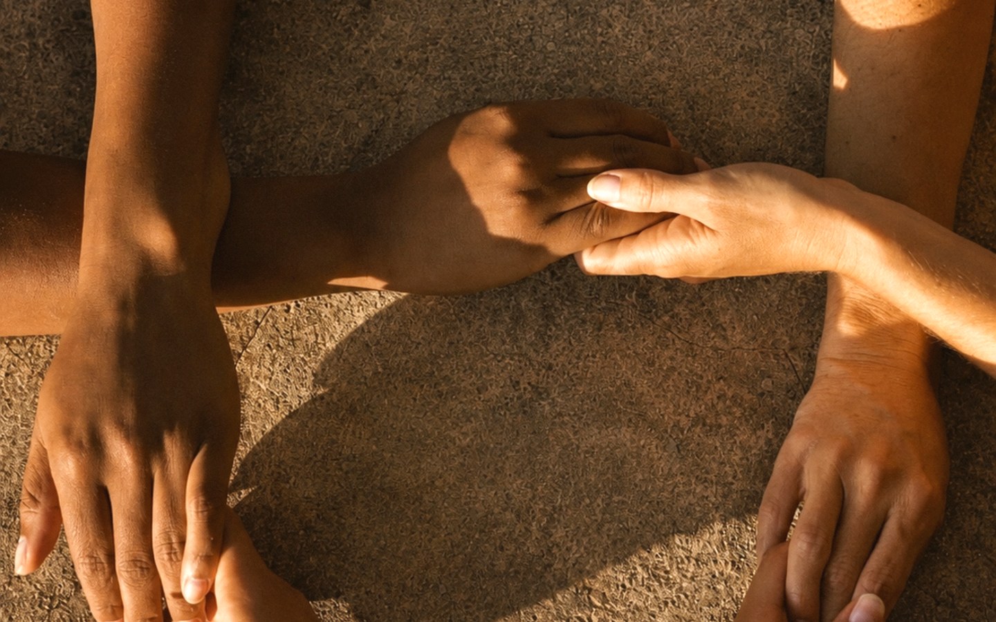 Several hands reaching toward each other on warm stone