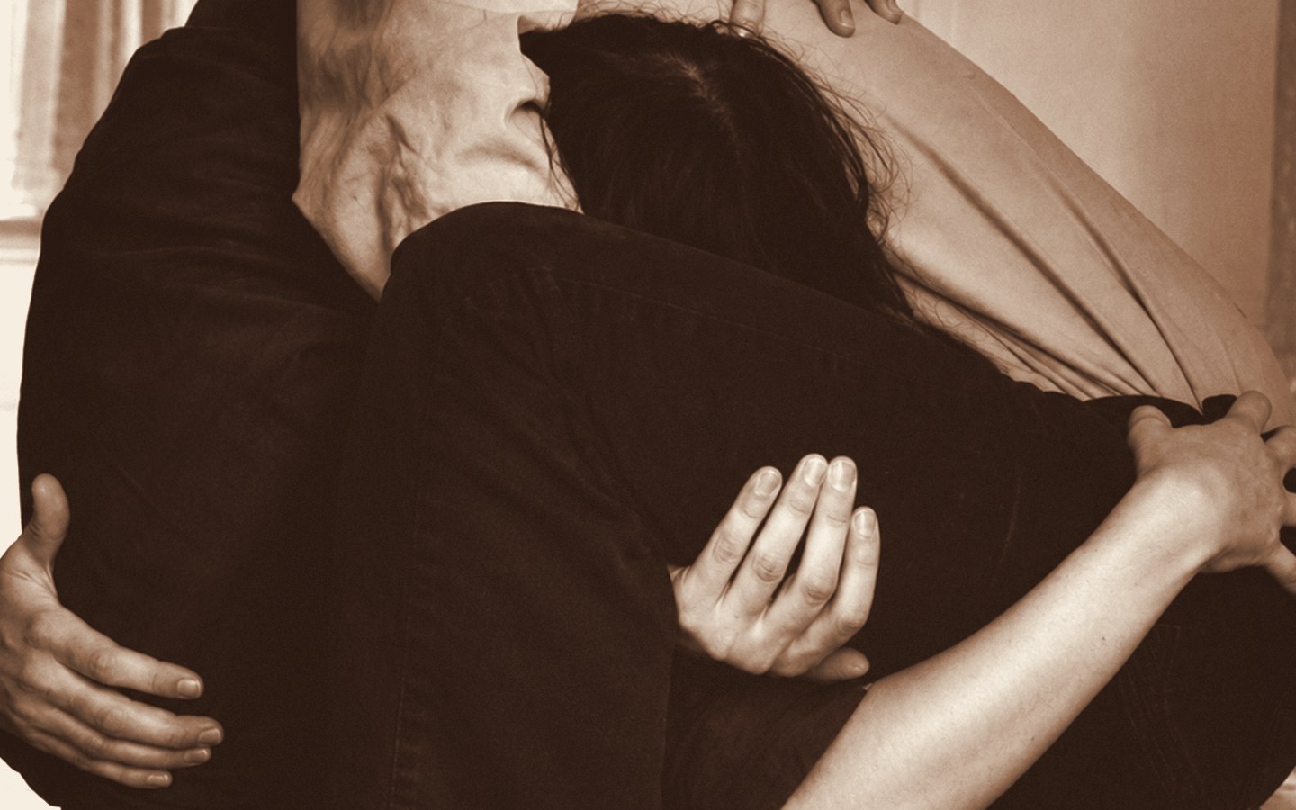 One person holding another gently, in warm light